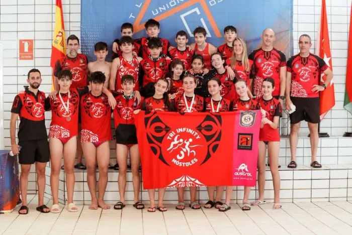 Niños y niñas de la escuela de triatlón Tri Infinity con la bandera del club